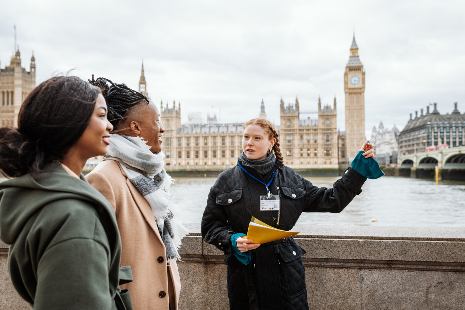 Young multi-ethnic tourist in London, followed by private tour guide. Tour guid showing Westminster bridge and Big Ben